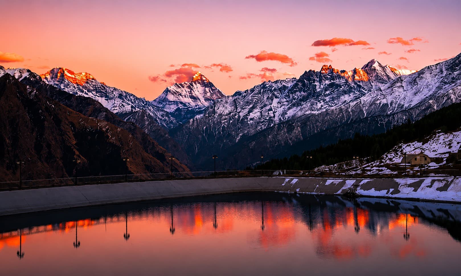 Snow-capped Himalayan peaks reflected in a still lake at sunset