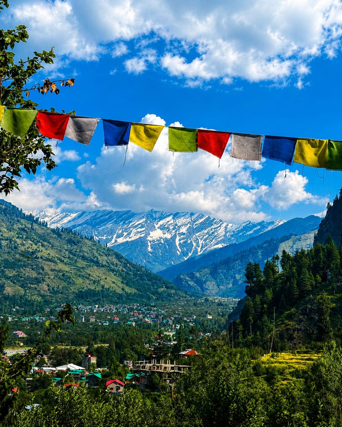 Prayer flags overlooking the Manali valley with snow-capped peaks behind