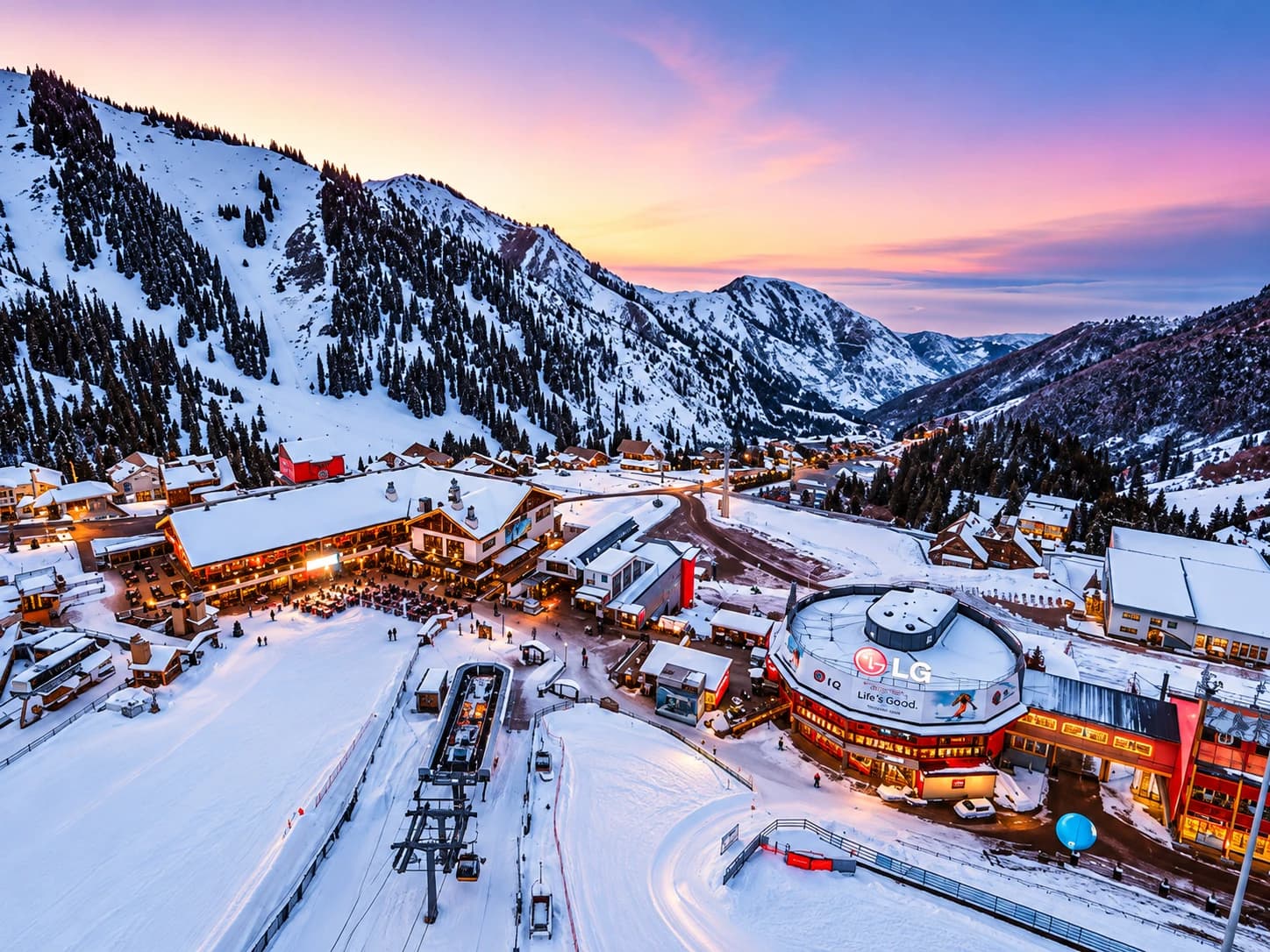 Shymbulak Ski Resort at dusk, with illuminated chalets and ski lifts against the snow-covered mountains