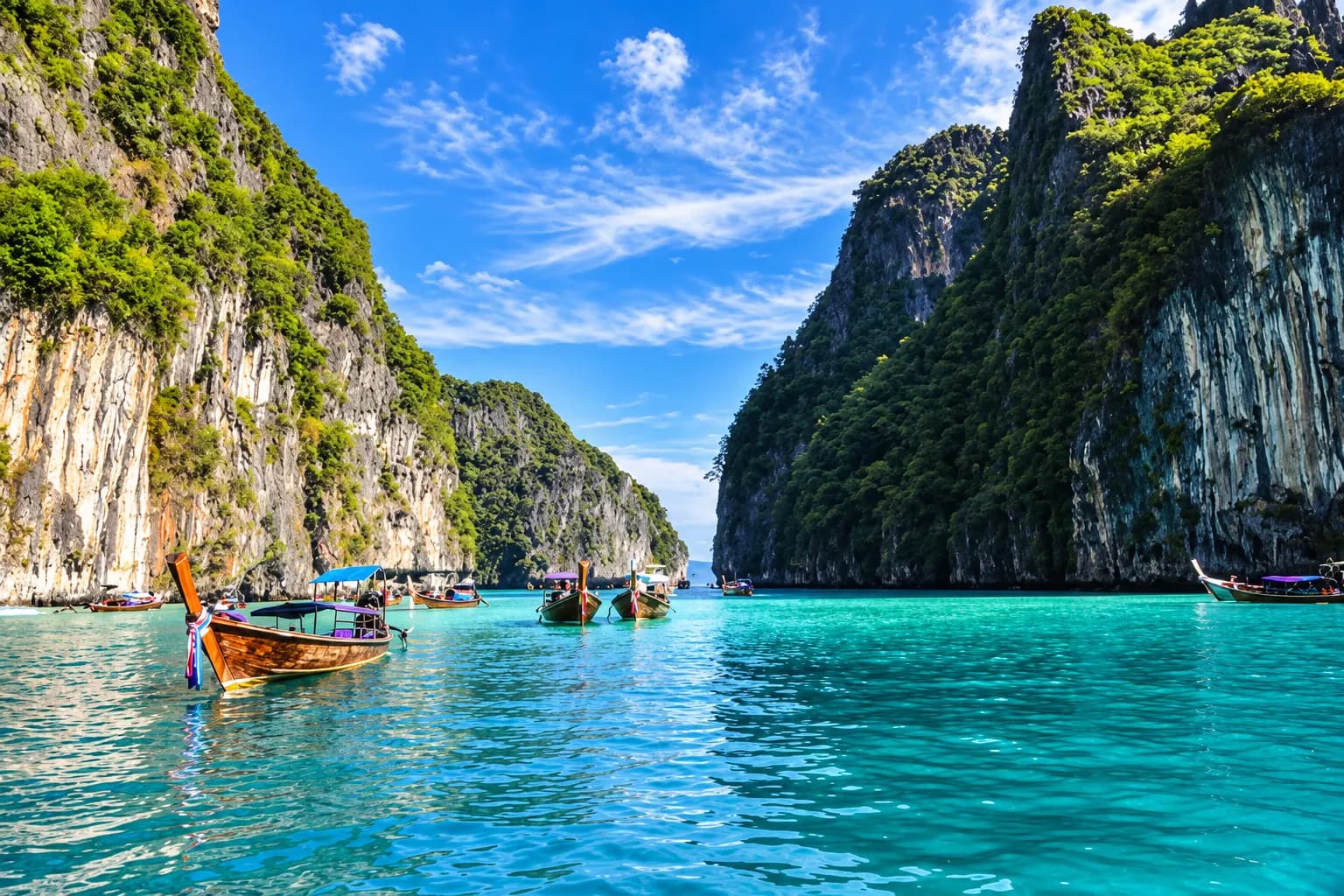 Longtail boats in a turquoise lagoon surrounded by limestone cliffs at the Phi Phi Islands, Thailand