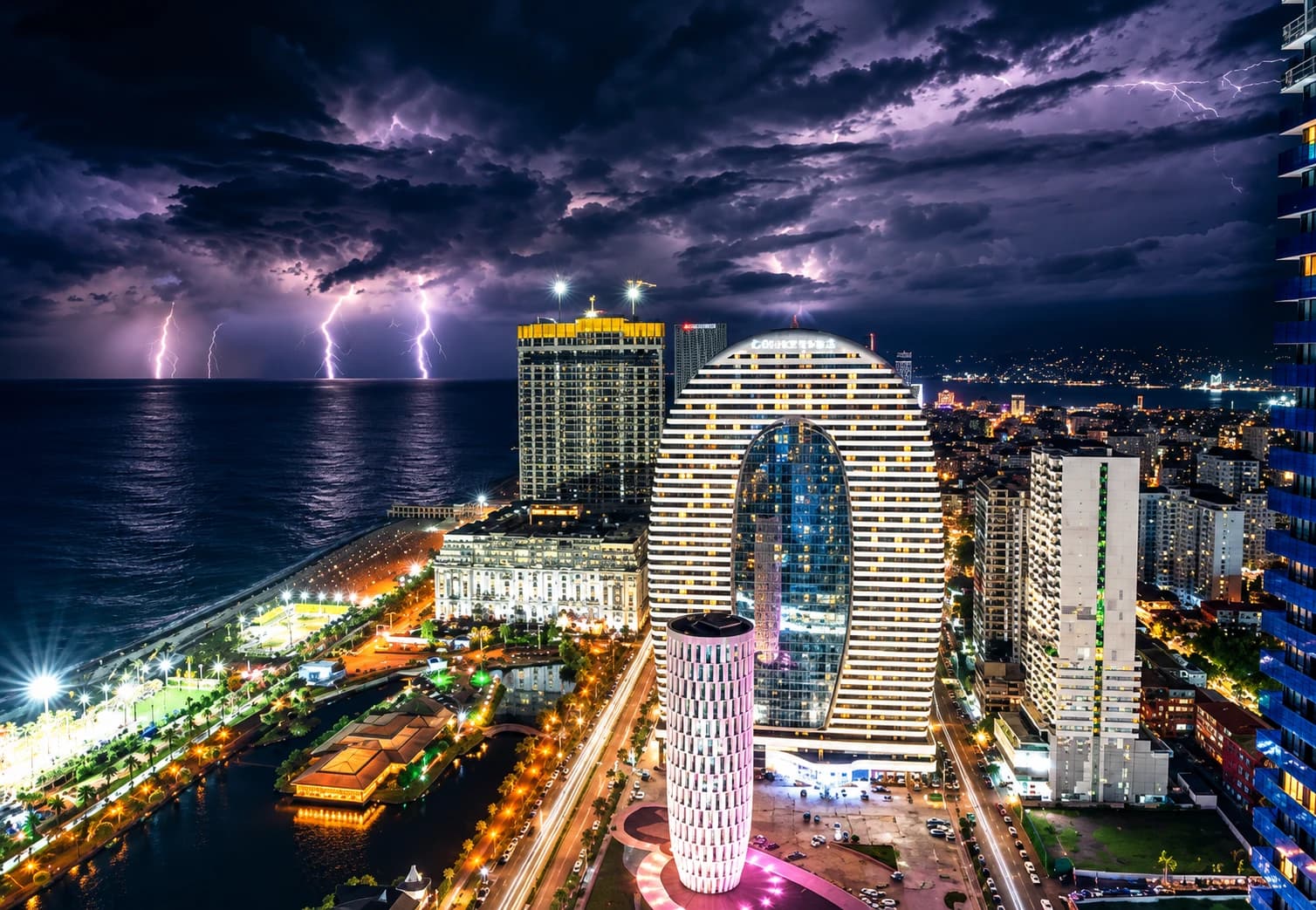 Batumi's illuminated skyline at night along the Black Sea coast, with lightning over the water